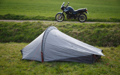 Das Zelt im Vordergrund auf einer Wiese, das Motorrad im Hintergrund