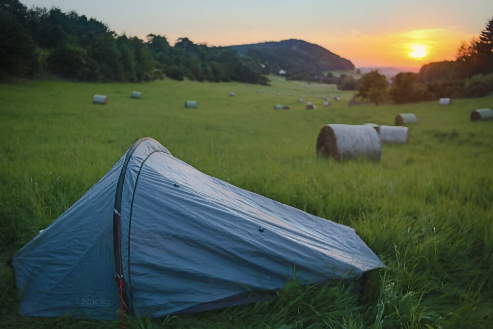 Zelt mit Heuballen und Sonnenuntergang im Hintergrund