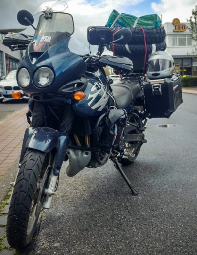 Triumph Tiger mit bei der ein Satz Reifen auf das Topcase gespant wurde.