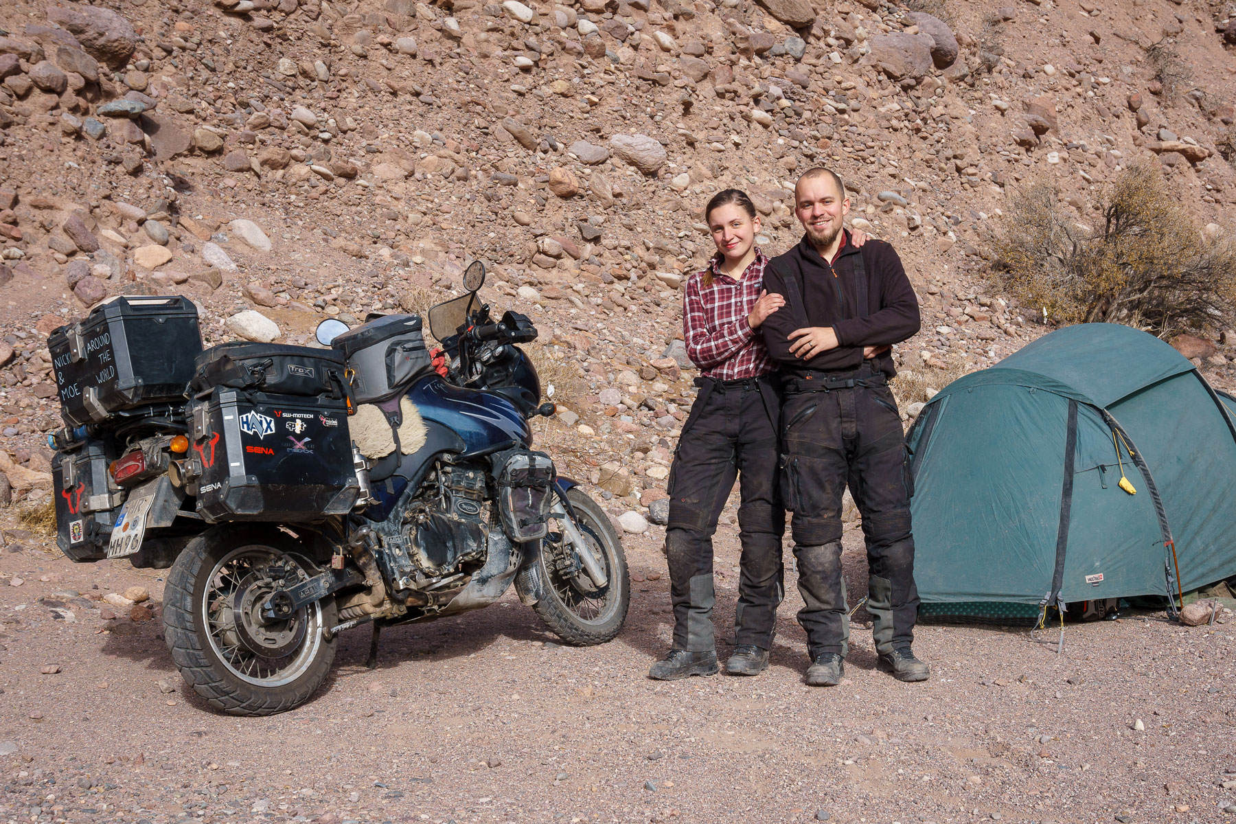 Nicki and Moe standing happily in front of the tent and the motorcycle