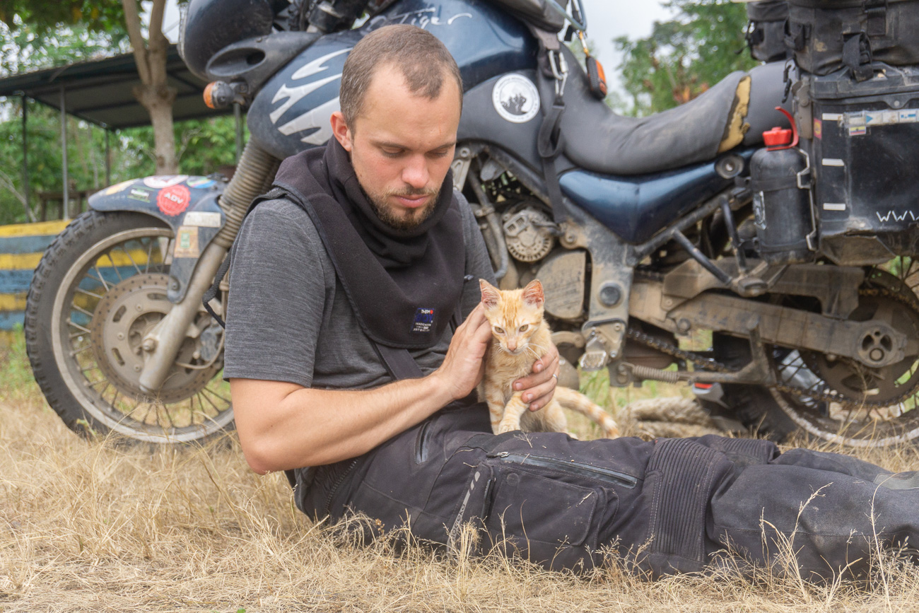 Cat on the lap of Moe in front of the motorcycle